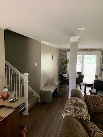 A living room with a couch , table , chairs and stairs.
