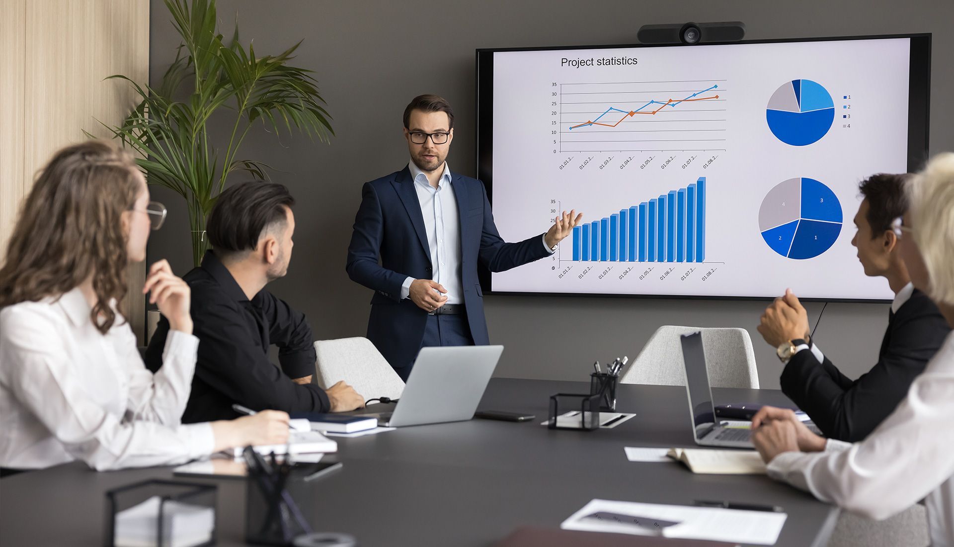 Man in suit presenting financial data to a group in a conference room.