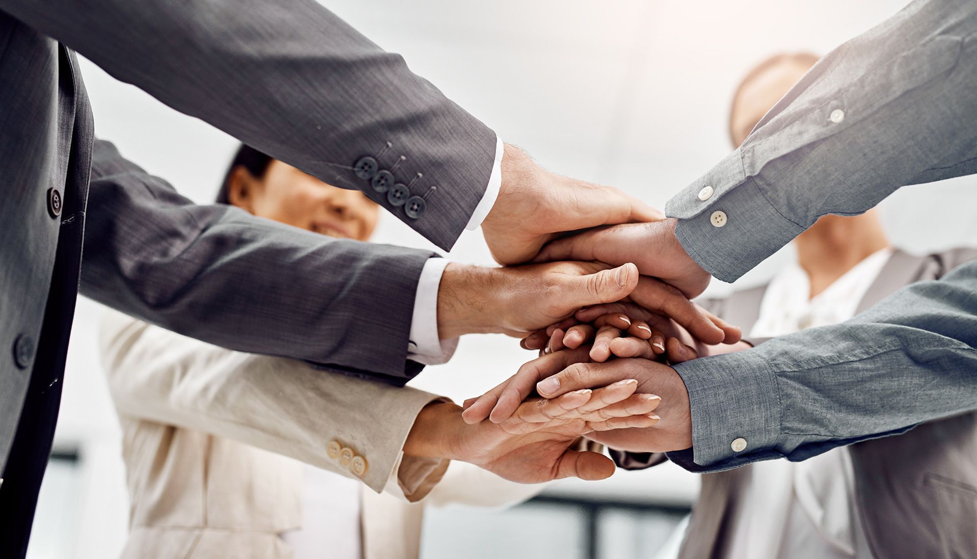 People's hands stacked together in a team huddle, symbolizing unity and collaboration.