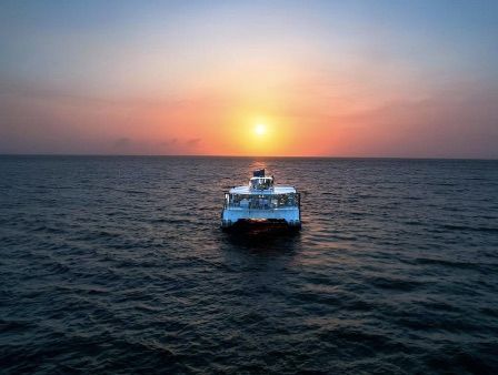 Un barco en aguas tranquilas, recortado contra una colorida puesta de sol.