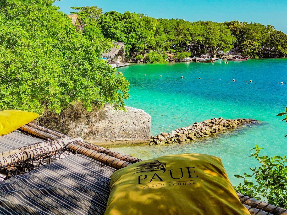 Laguna tropical con agua turquesa, exuberantes árboles verdes y cojines amarillos.