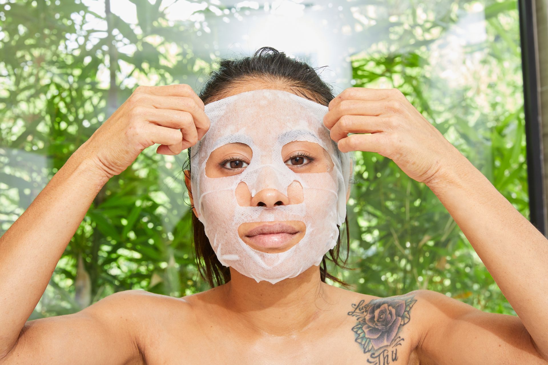A woman is taking off a sheet mask from her face.
