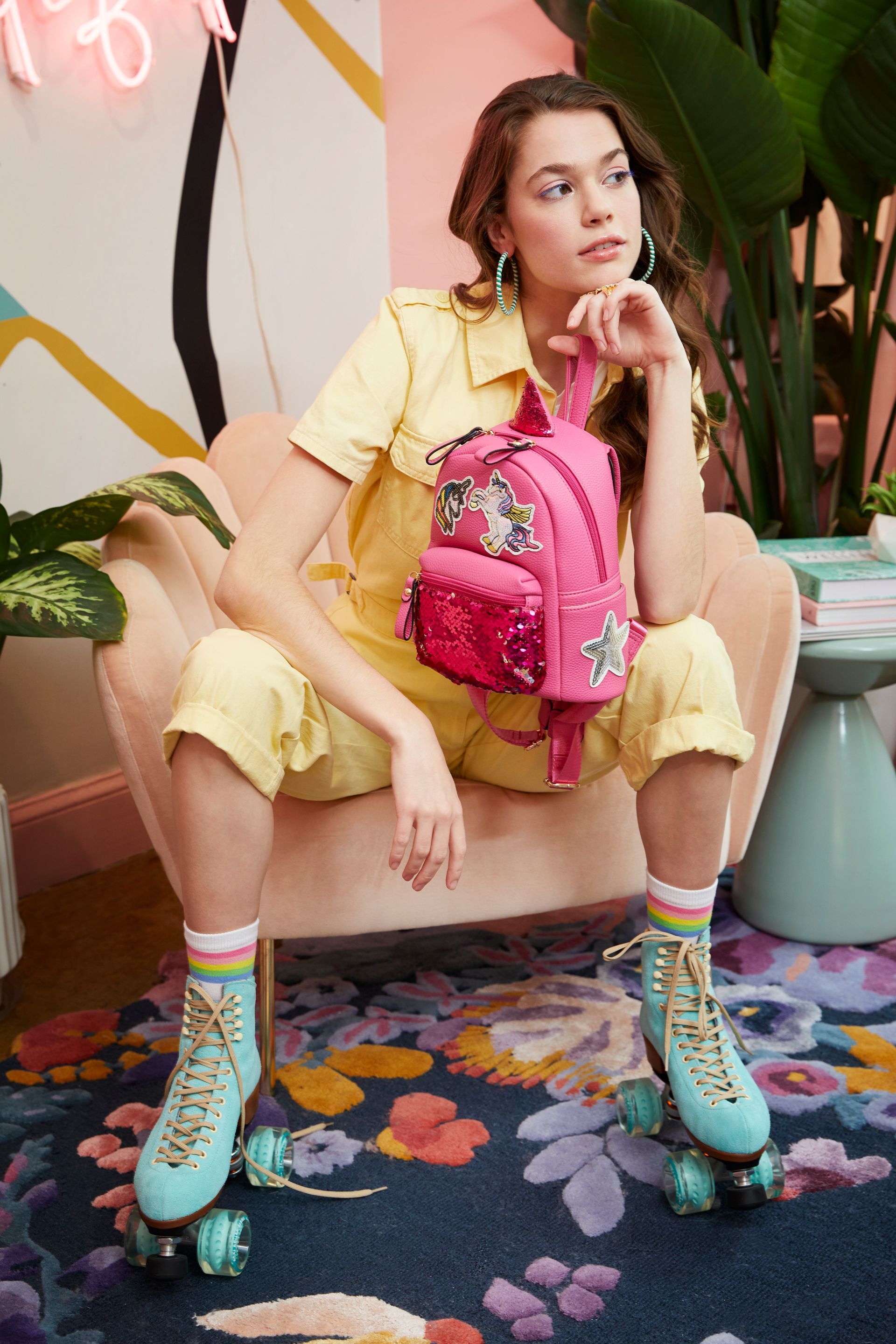A woman is sitting in a chair wearing roller skates and a pink backpack.