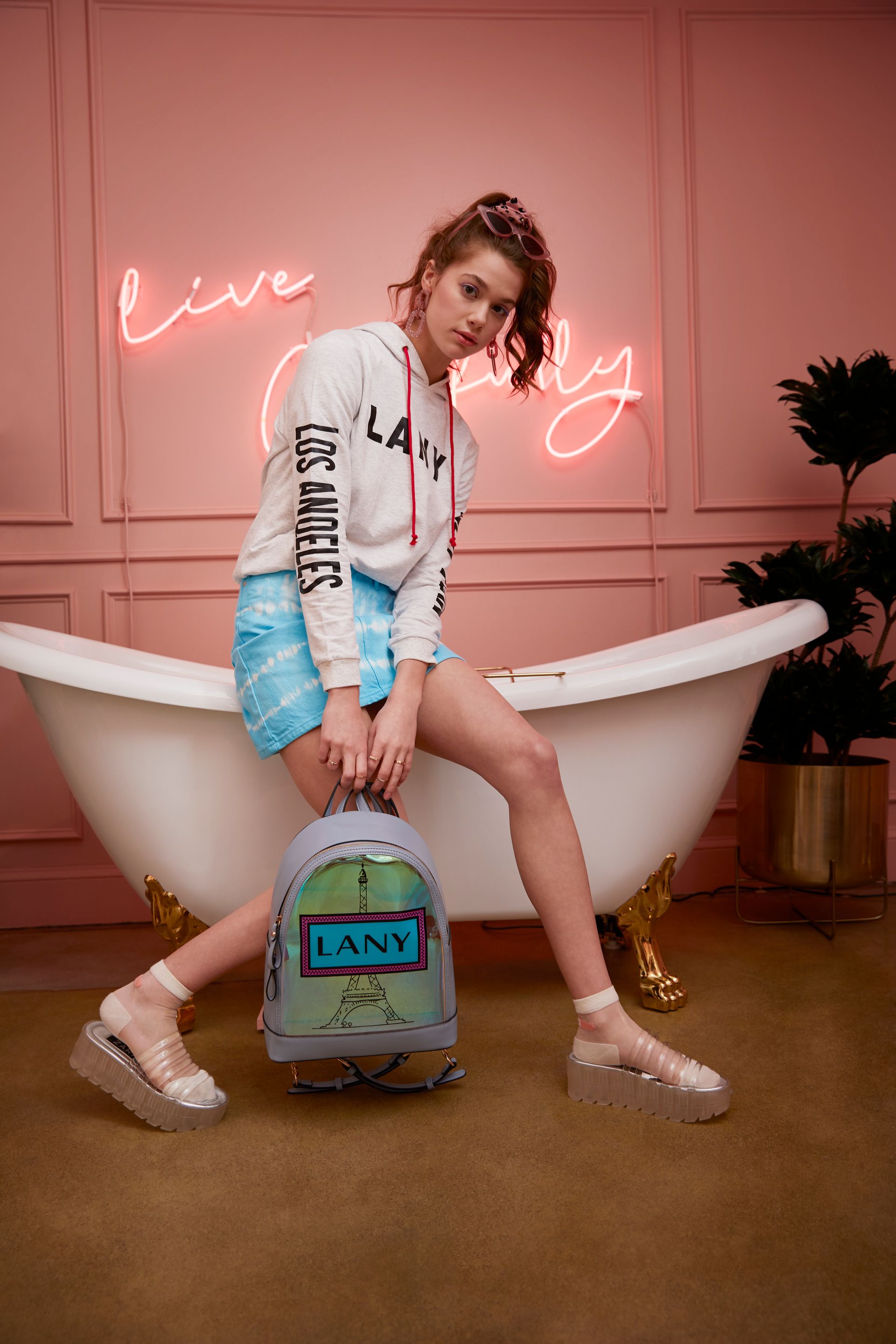 A woman is sitting on a bathtub holding a backpack.