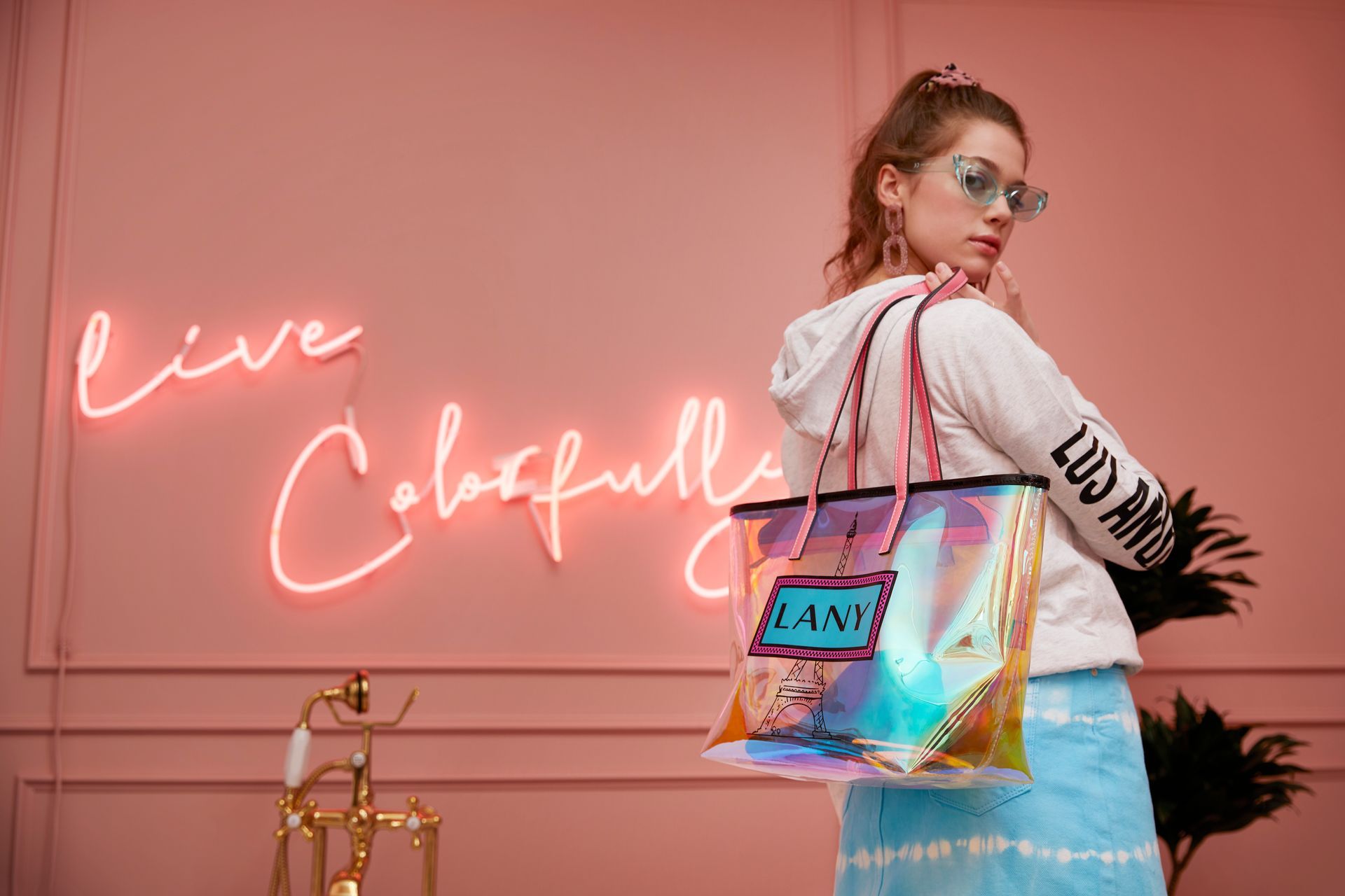 A woman is standing in front of a neon sign that says `` live colorfully ''.