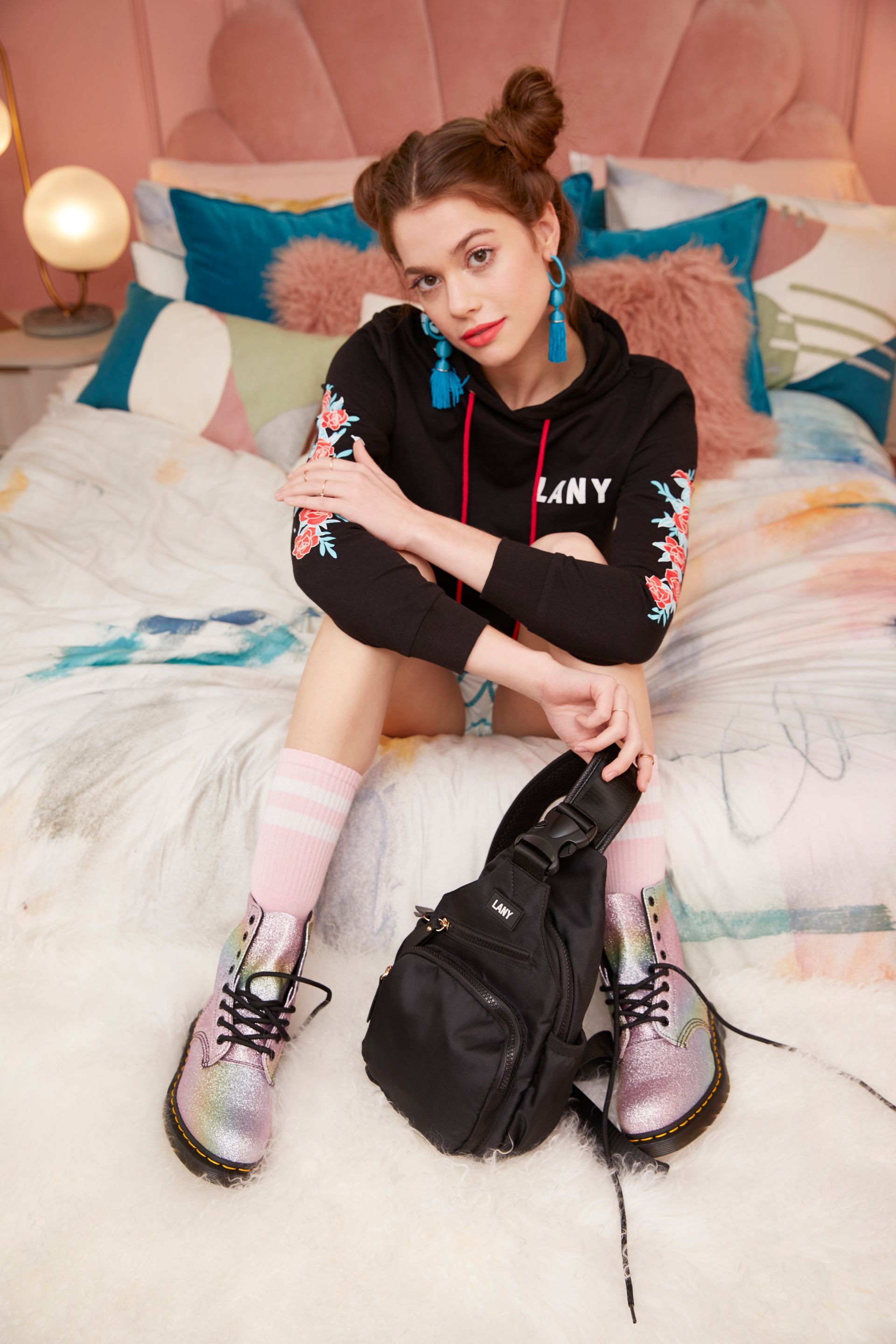 A woman is sitting on a bed with a backpack.