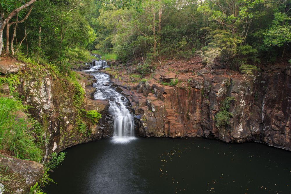 Waterfall Cascading Into a Dark Pool Surrounded by Rocks — All Pest Solutions in Alstonville, NSW