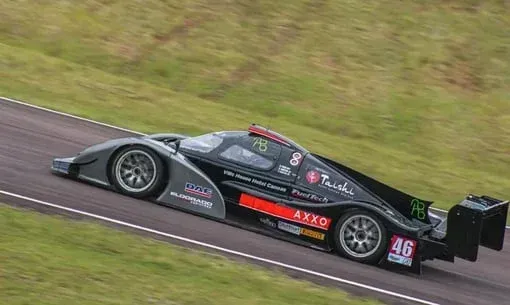 Um carro de corrida preto está passando por uma pista de corrida.