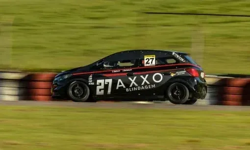 Um carro de corrida preto está passando por uma pista.