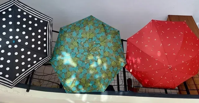 Tre ombrelli esagonali aperti: nero a pois, verde acqua a fiori, rosso a pois bianchi.