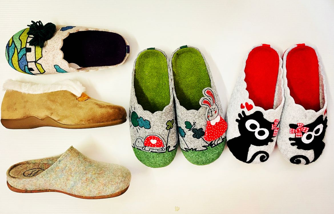 Varietà di pantofole di feltro colorate disposte su una superficie bianca.