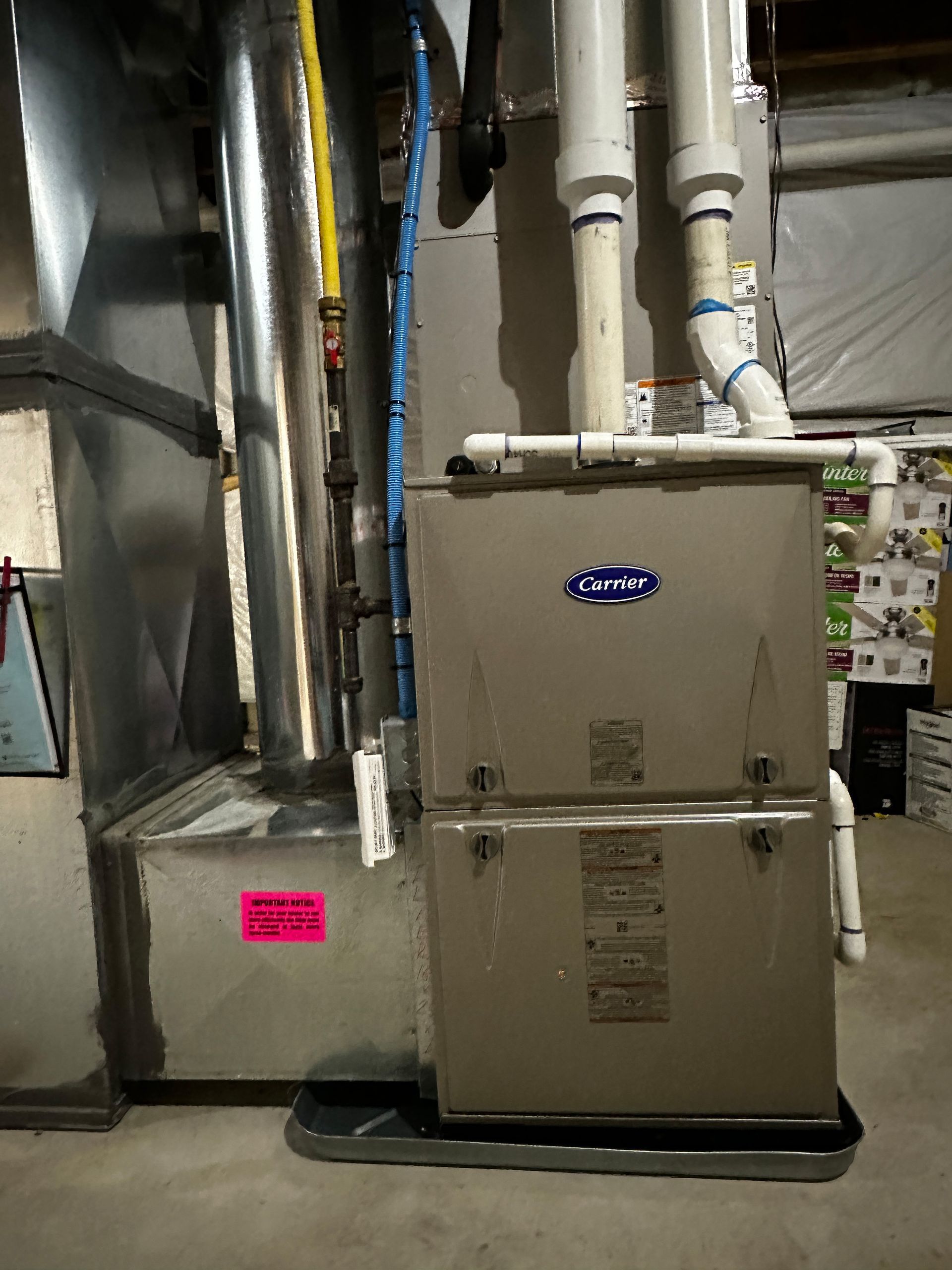 A Carrier HVAC unit in a basement. Ductwork and pipes are visible.