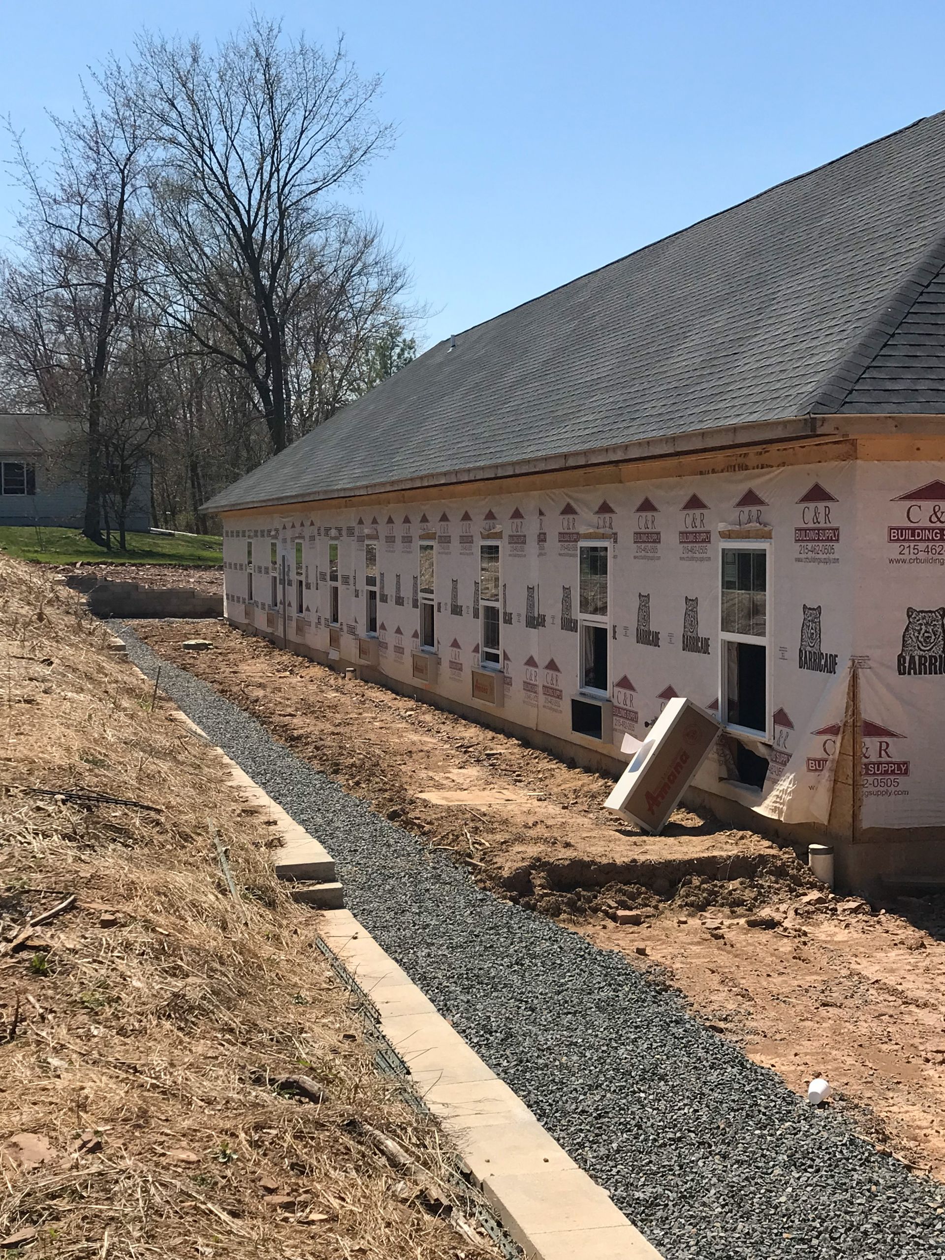 Building under construction with a gravel drainage trench alongside it.