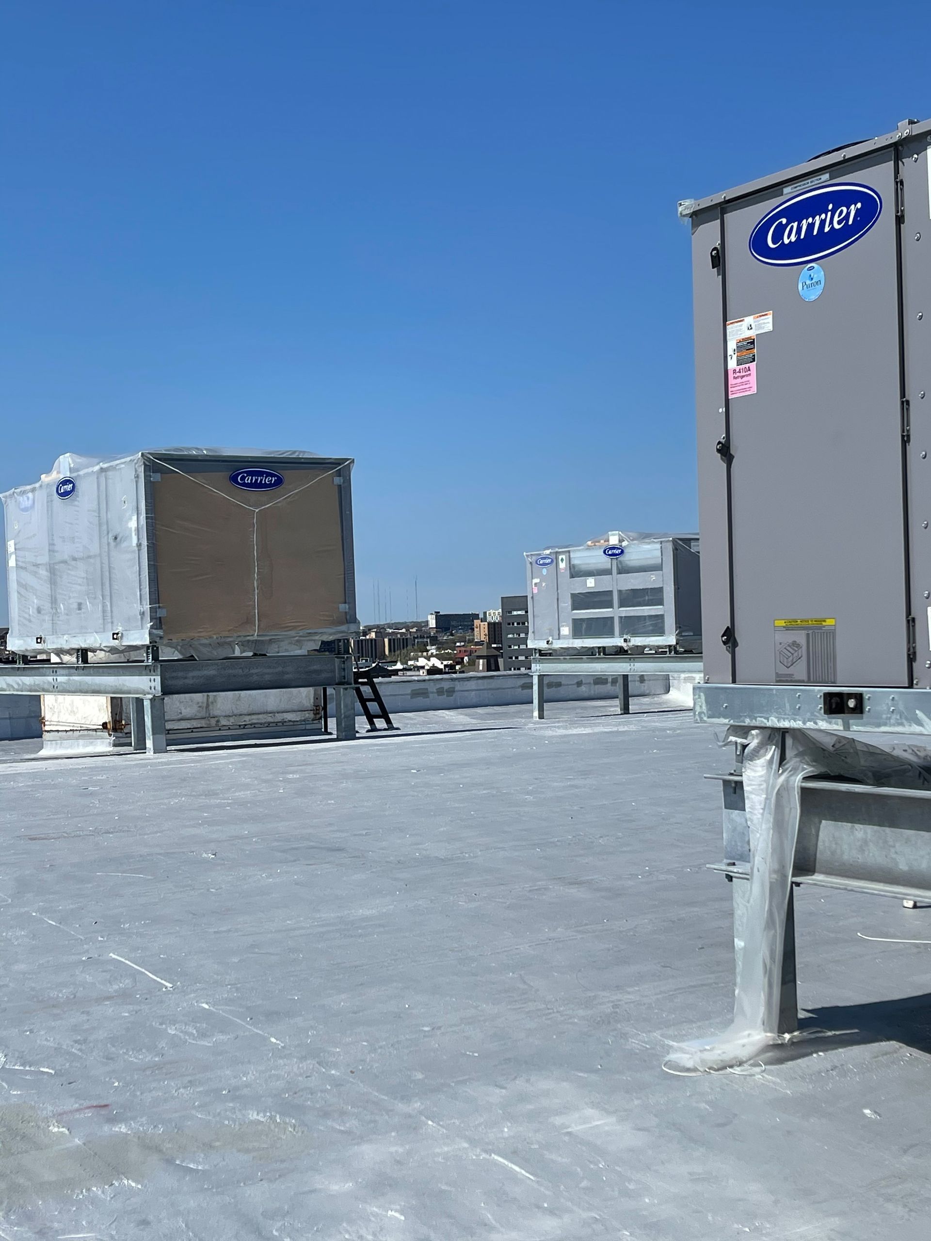 Rooftop with Carrier HVAC units on a bright day.  Blue sky overhead.