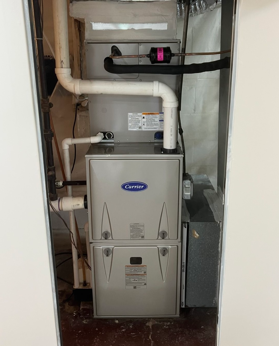 Furnace unit inside a utility closet, with ductwork and pipes.