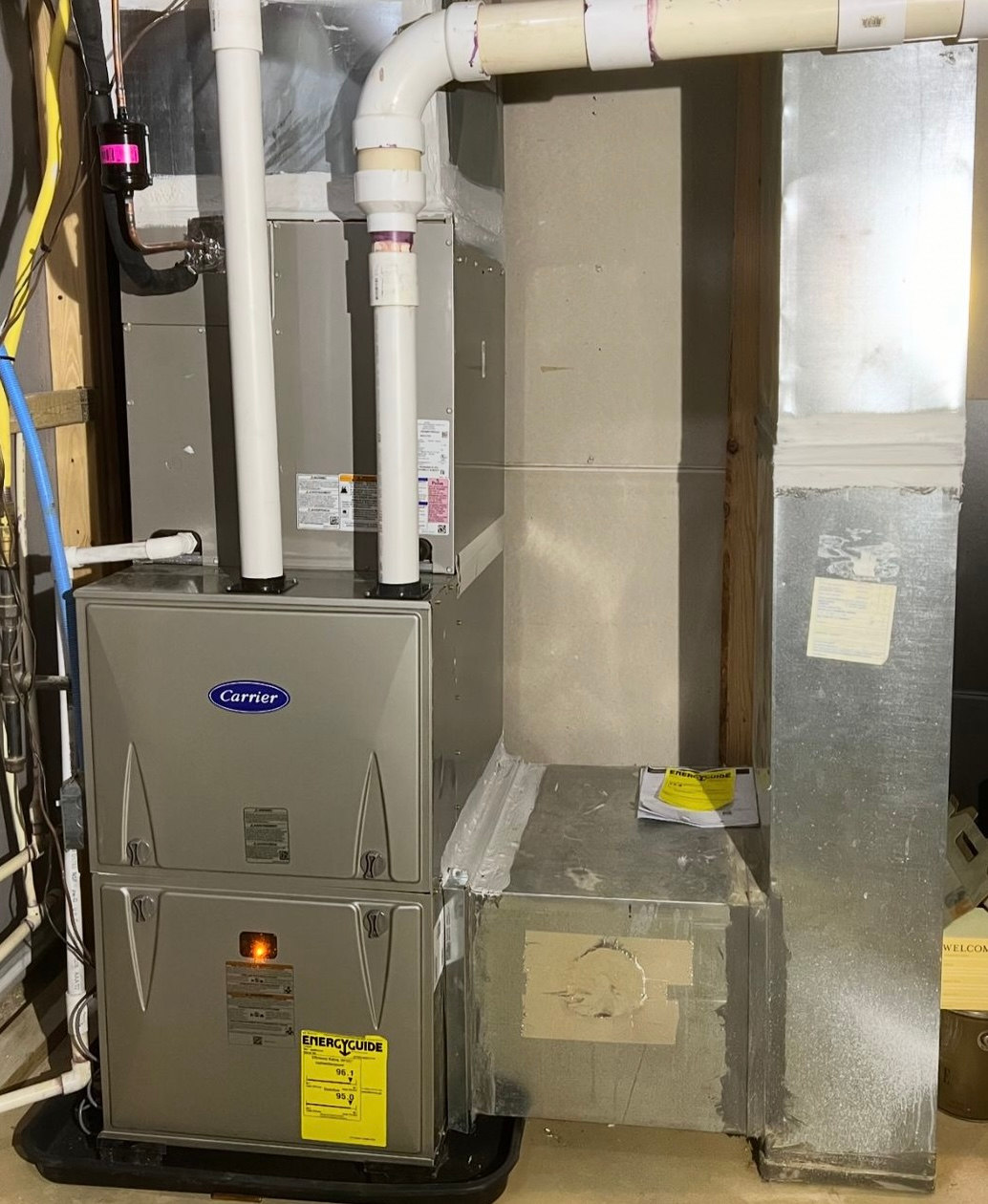 A Carrier furnace system with ductwork in a basement setting. Gray and white colors.