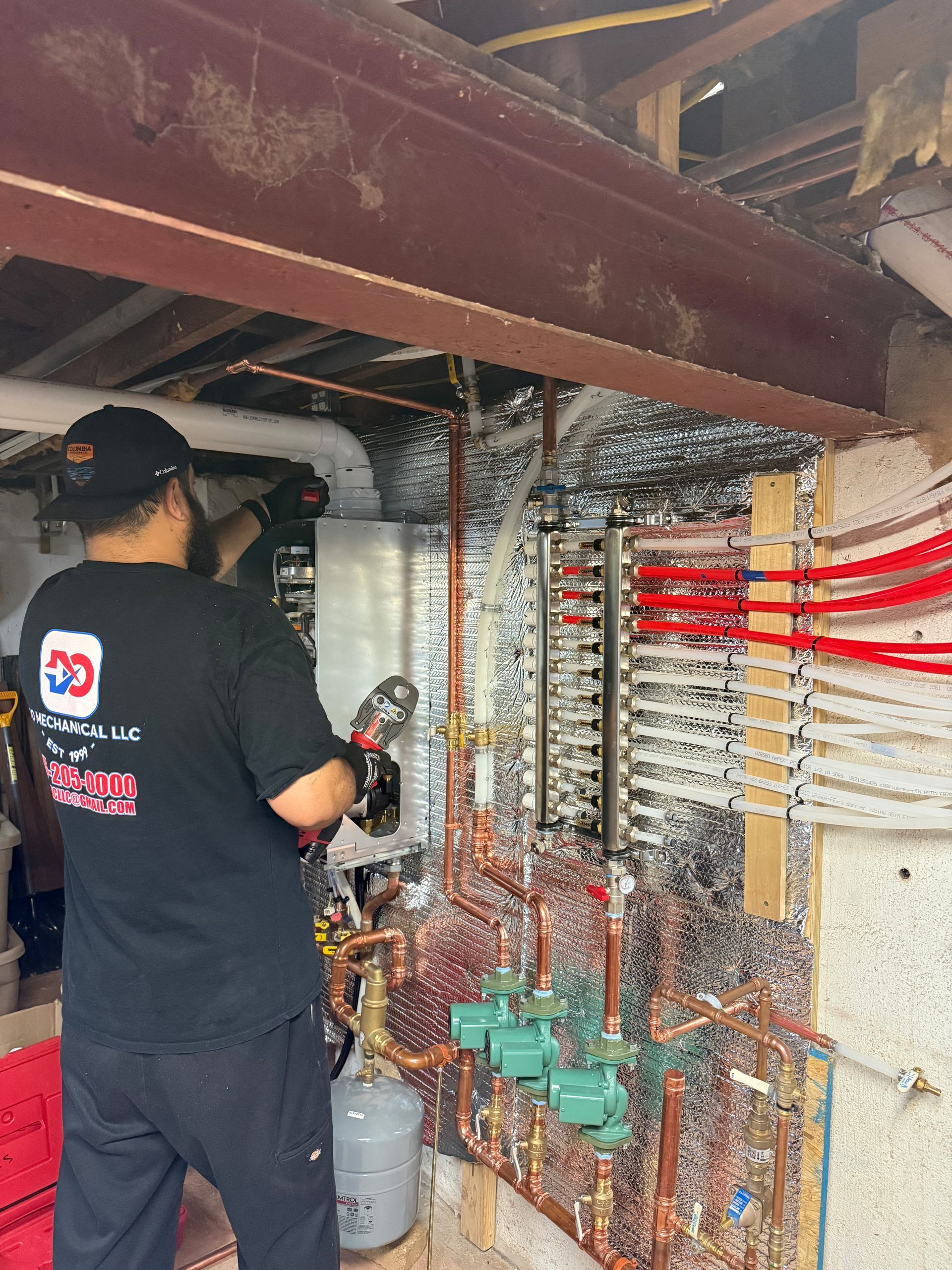 Man installing plumbing with copper pipes and a red toolbox in a basement.