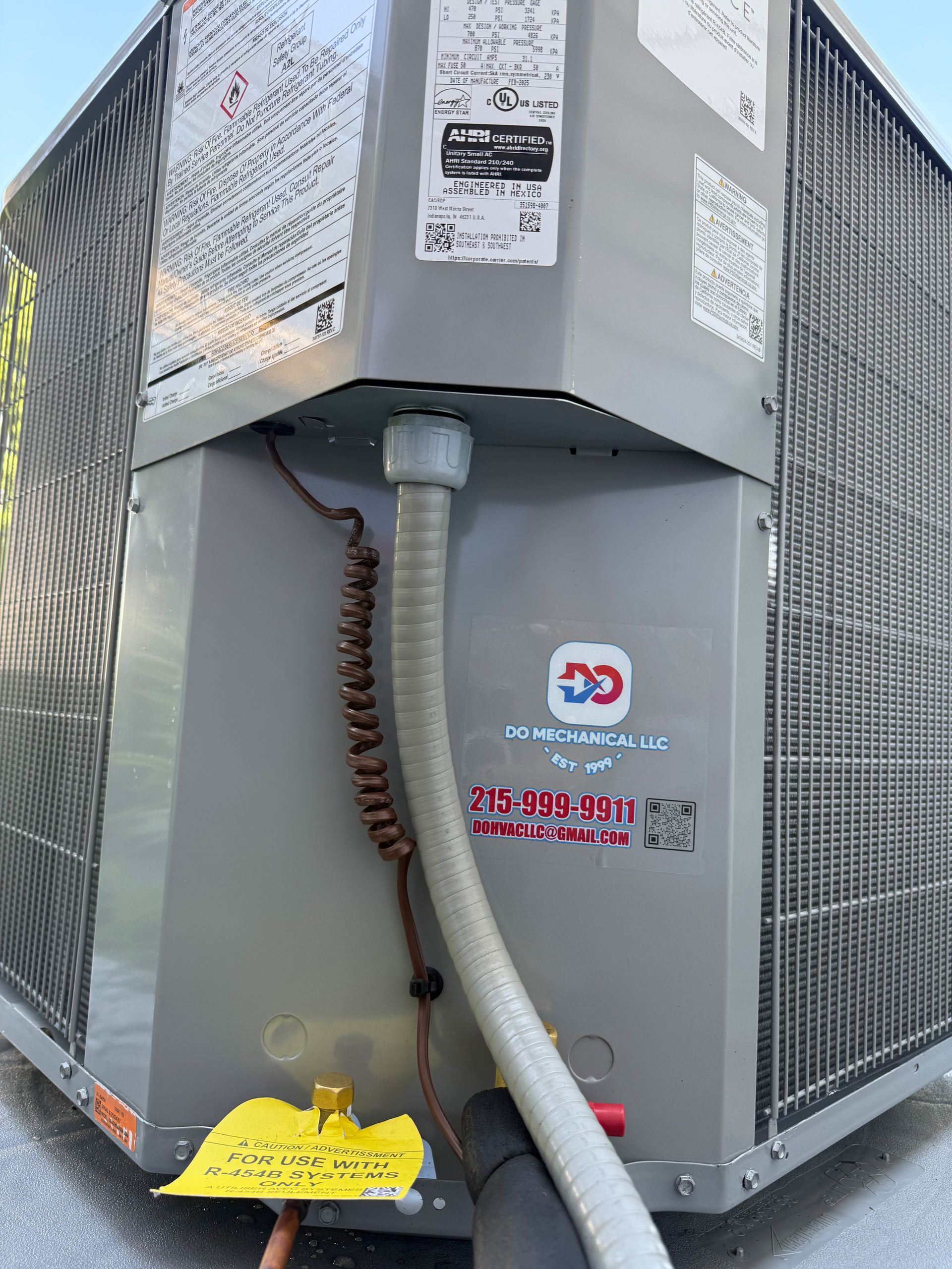 Exterior AC unit with gray metal casing, protective grill, and coiled electrical cord.