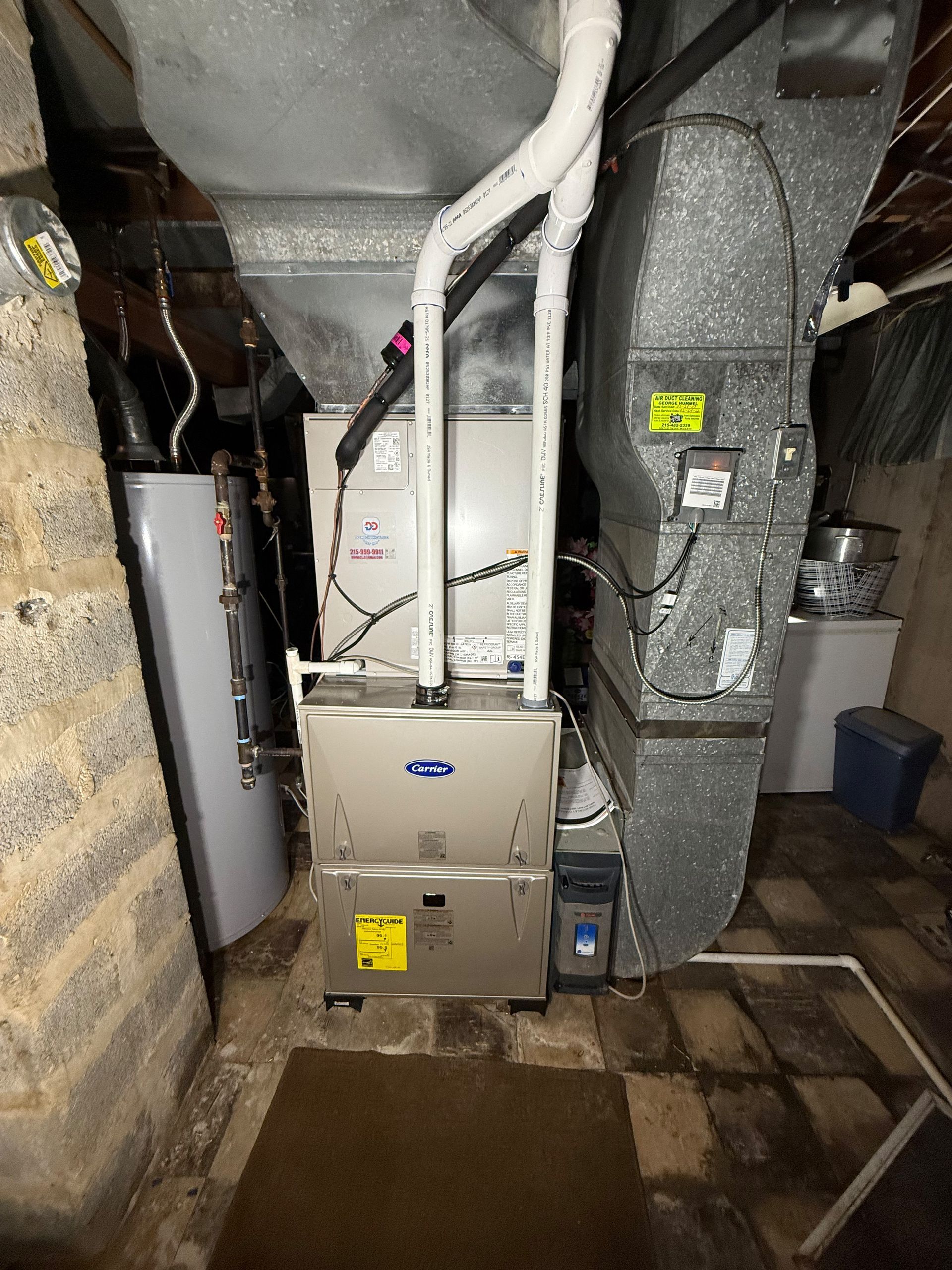 Furnace and water heater in a basement. Metal and brick construction.