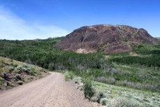 A dirt road in the mountains with a mountain in the background.