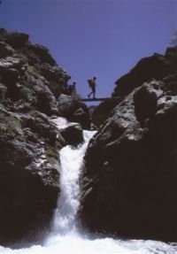 A man is crossing a bridge over a waterfall