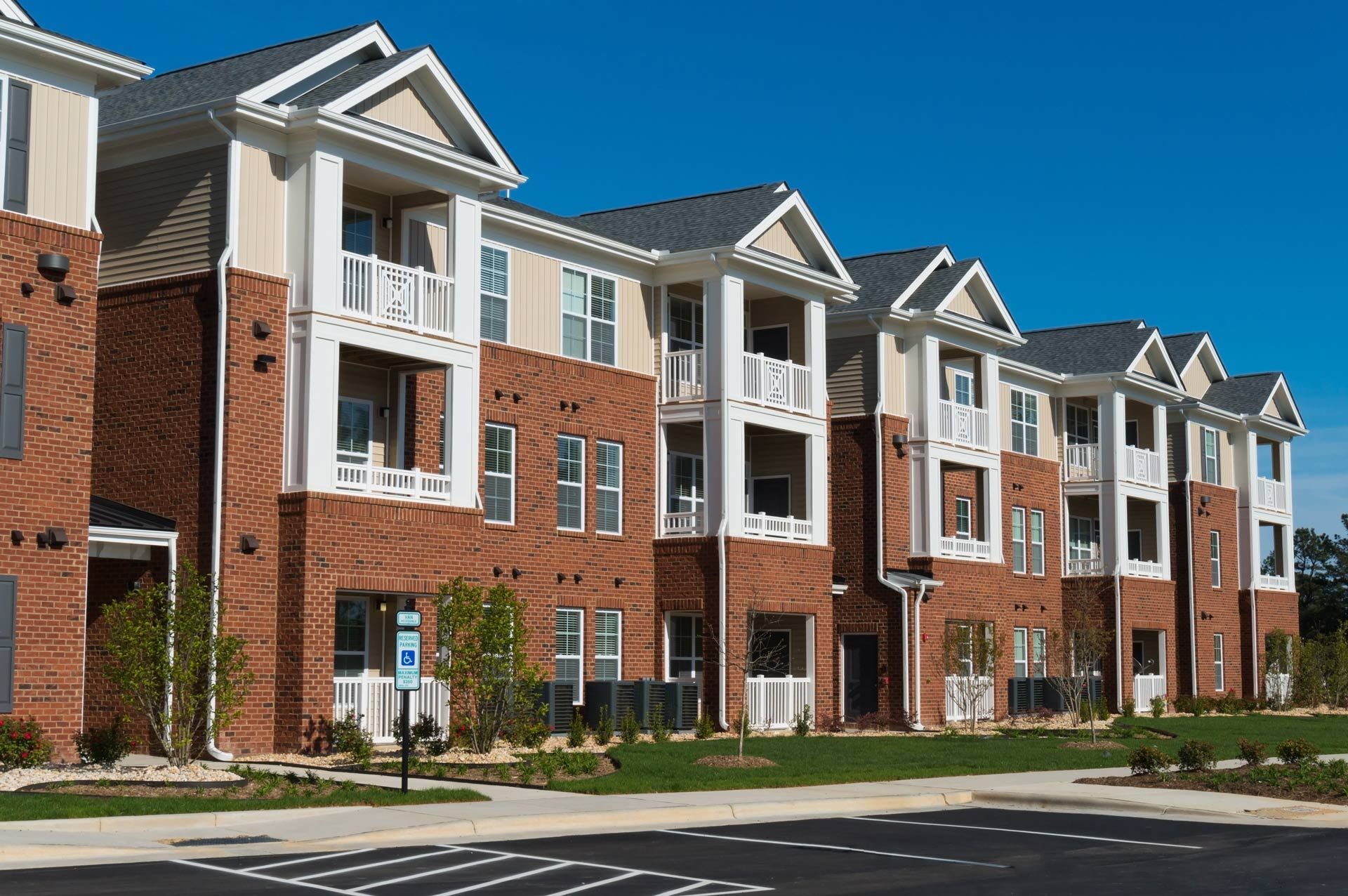 Multi-story brick apartment building with balconies under a clear