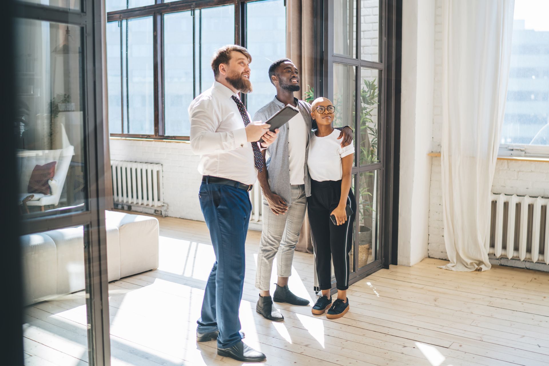 Real estate agent showing an apartment to a smiling black couple.
