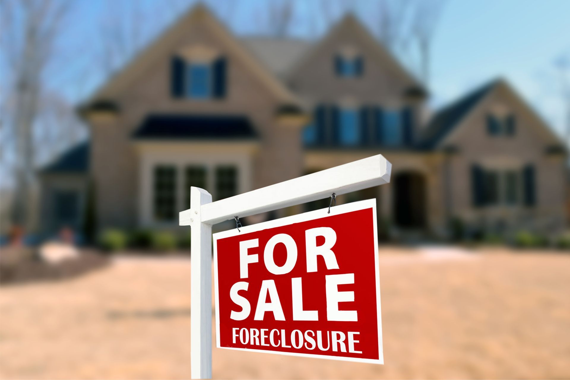 Foreclosure sign in front of a blurred house.
