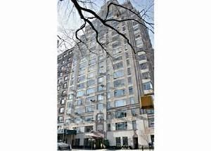 A tall, beige, multi-story apartment building in New York City with numerous windows, seen from a low angle.