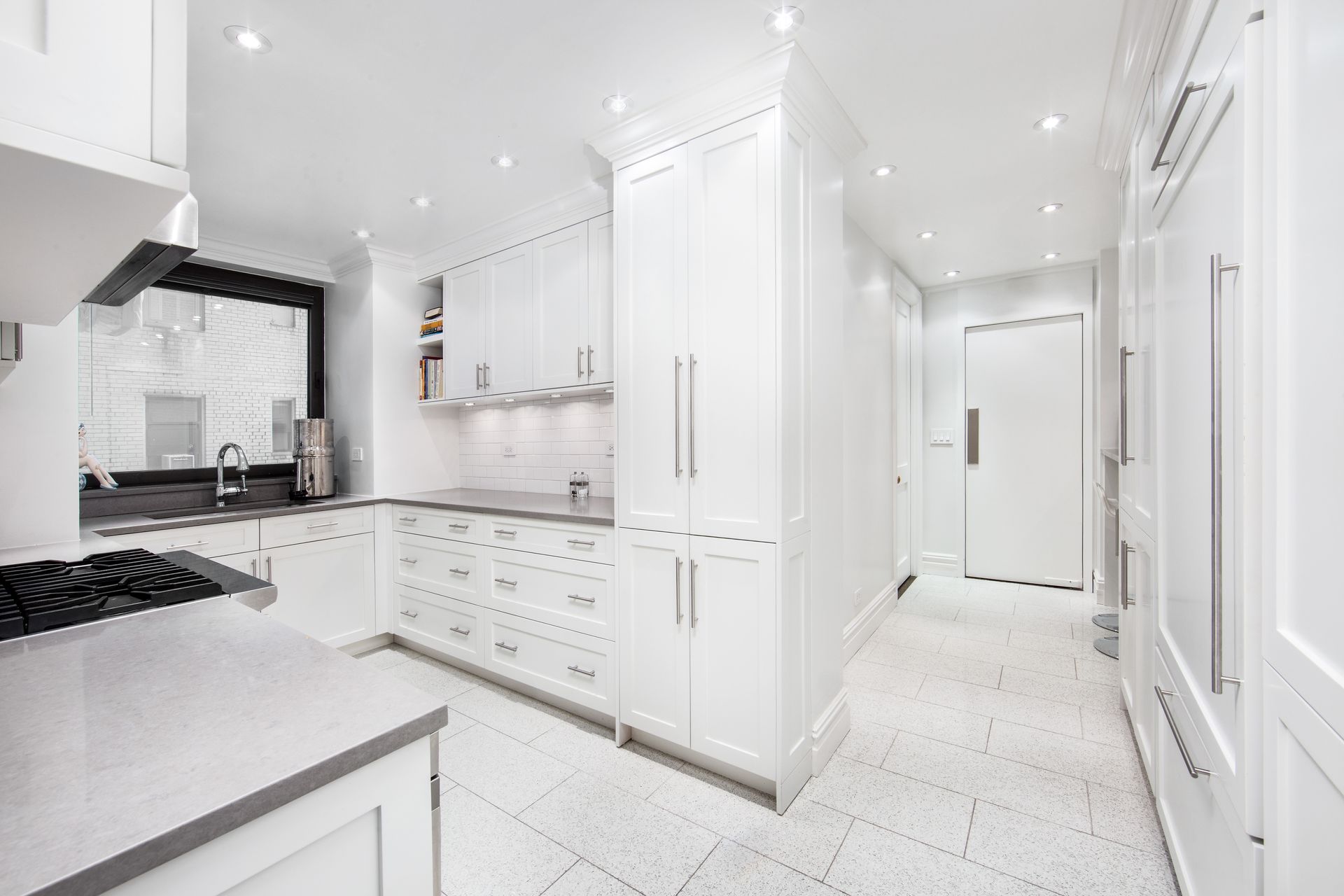 Bright, modern kitchen with white cabinetry, gray countertops, and tiled floors.