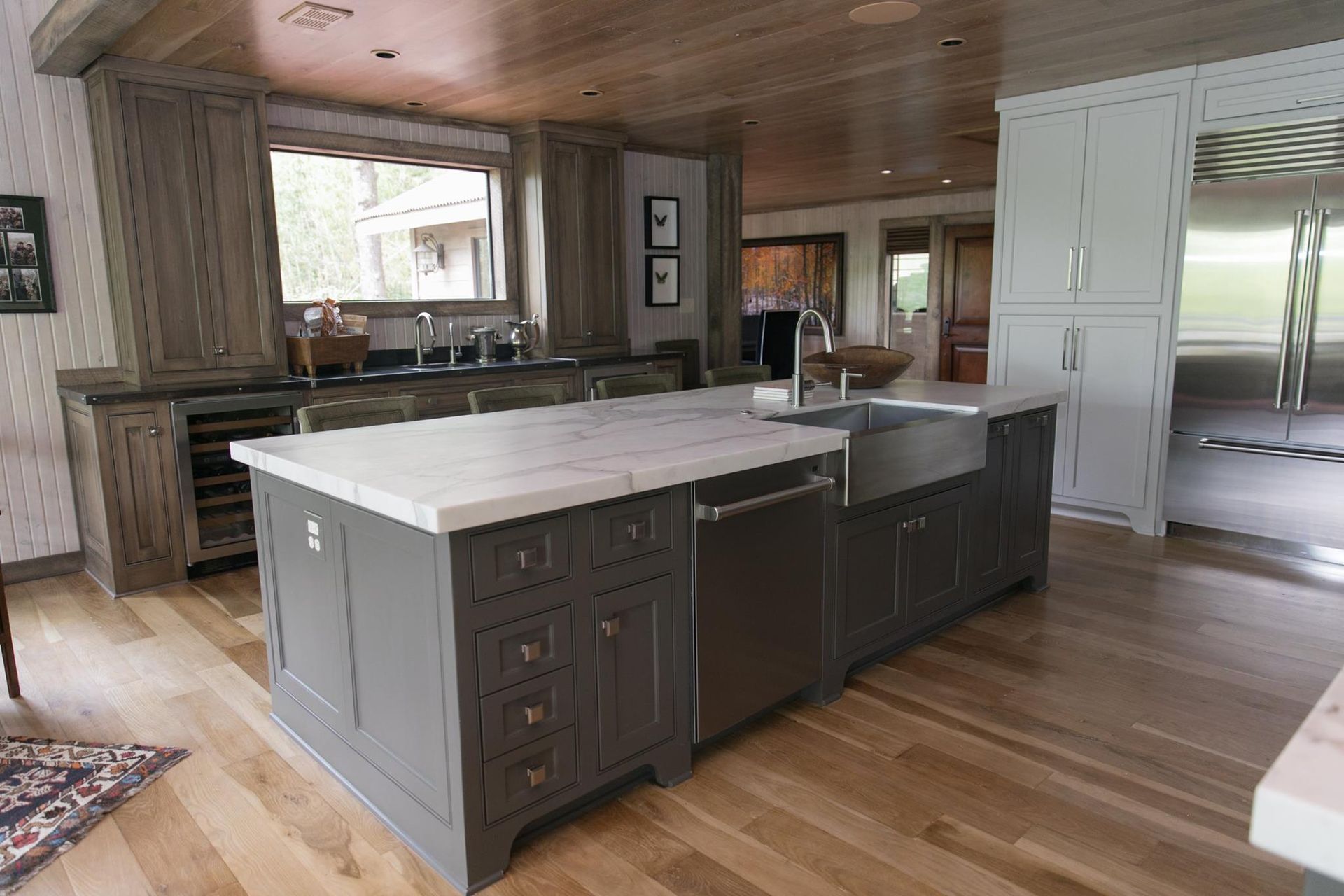 Kitchen with gray island, white countertop, stainless steel appliances, and wood cabinets.
