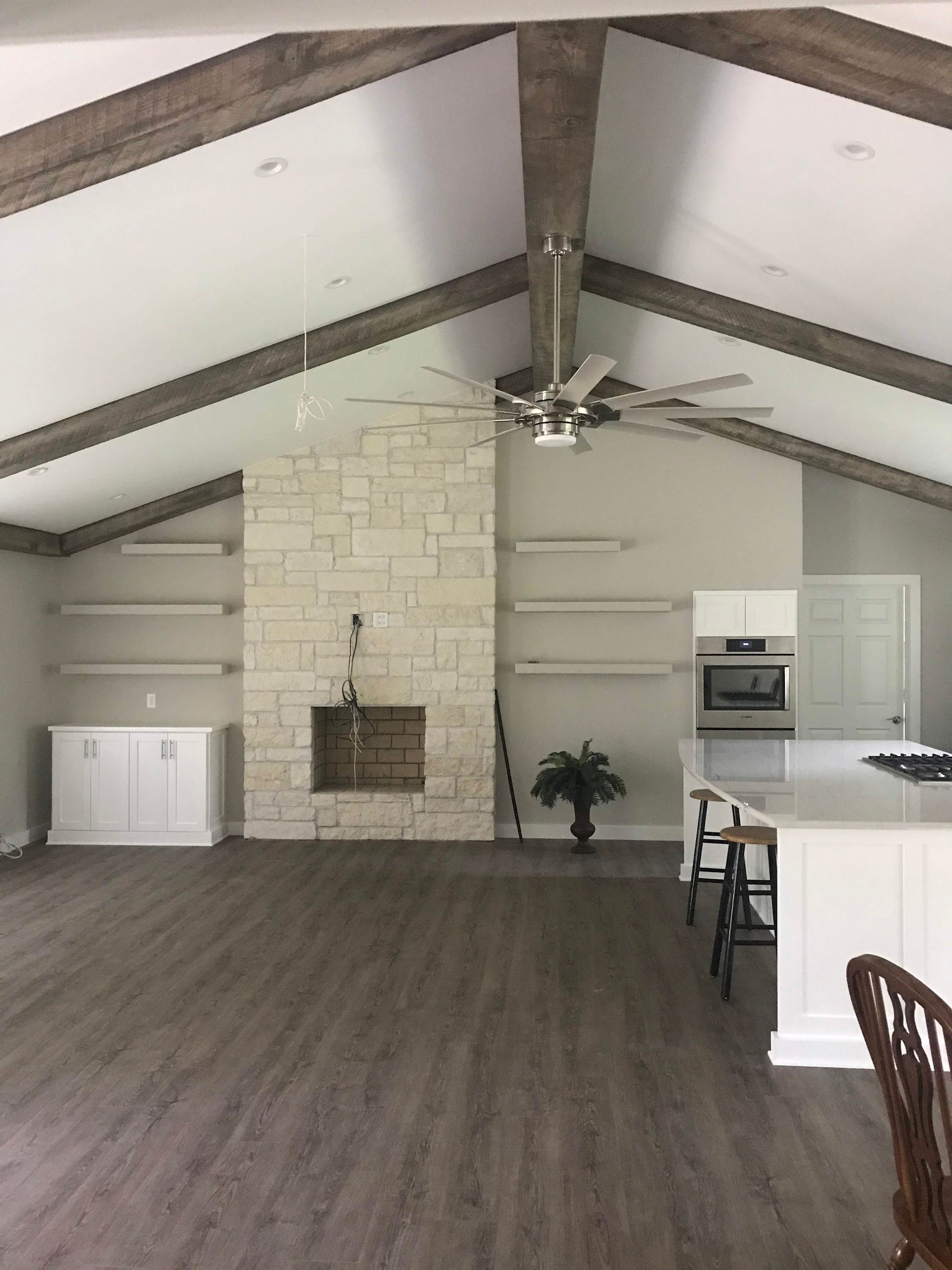 Spacious living room with vaulted ceiling, stone fireplace, and exposed wood beams.