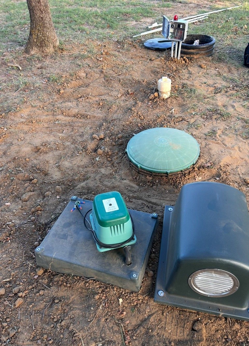 A green pump is sitting on top of a concrete platform in the dirt.