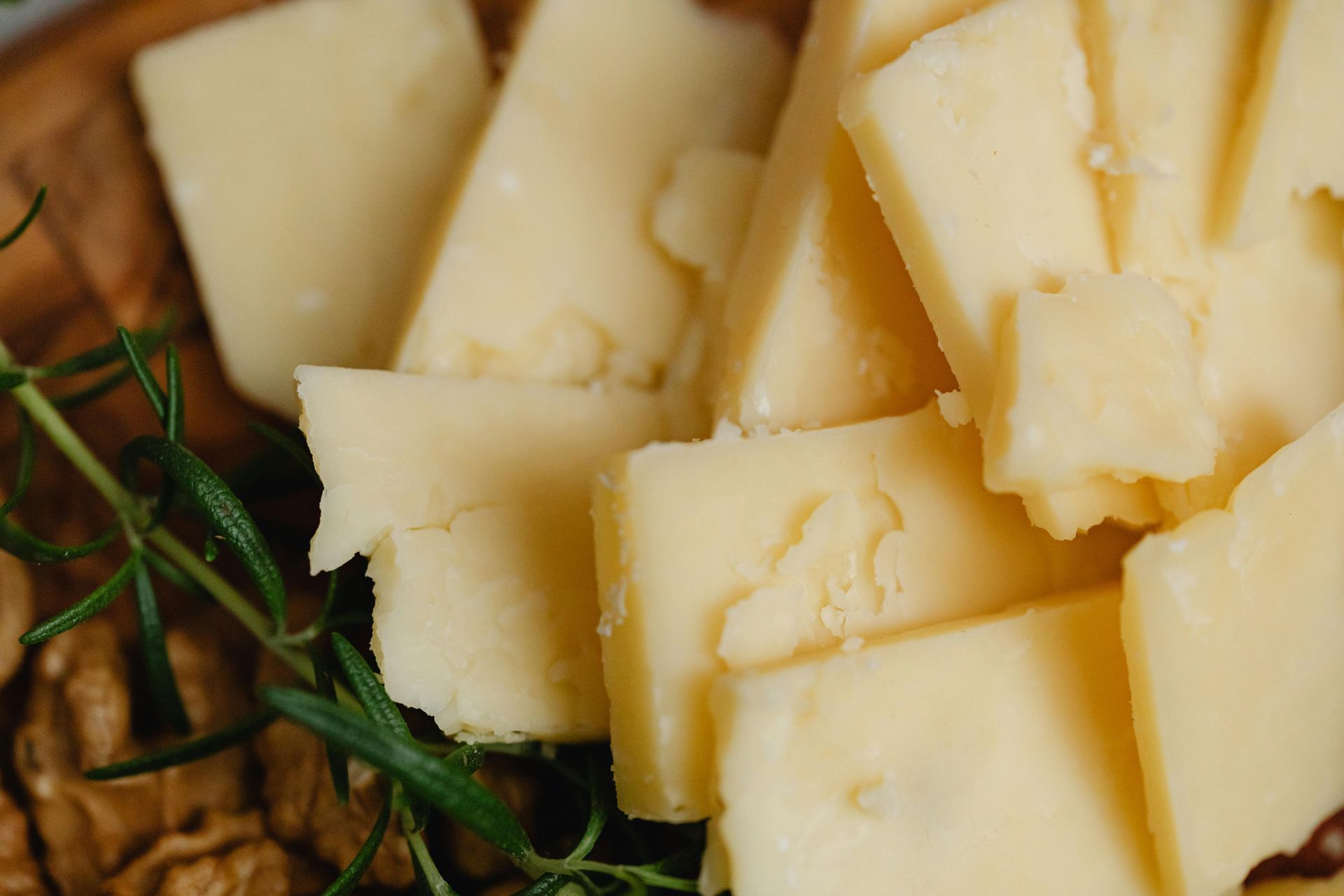 Surtido de lonchas de queso blanco adornadas con romero sobre una tabla de madera.
