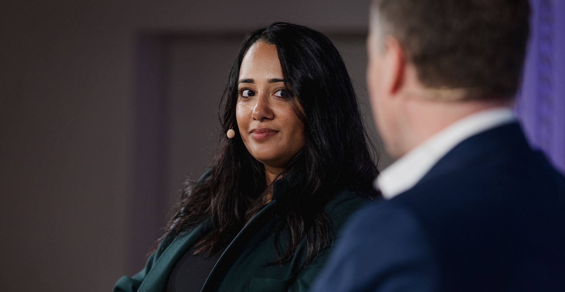 A photo taken by Ash Garwood of a woman listening to a panel at a town-hall style corporate event.