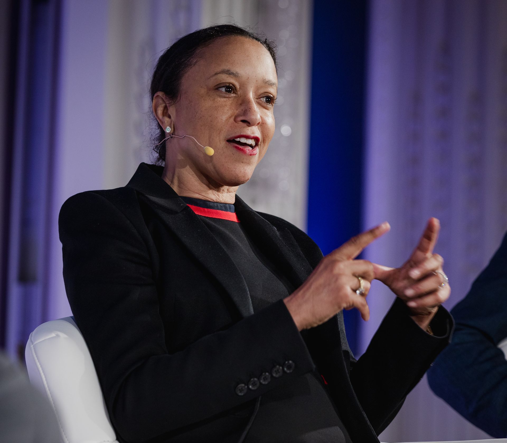 A photo taken by Ash Garwood of a woman talking to a panel at a town-hall style corporate event.