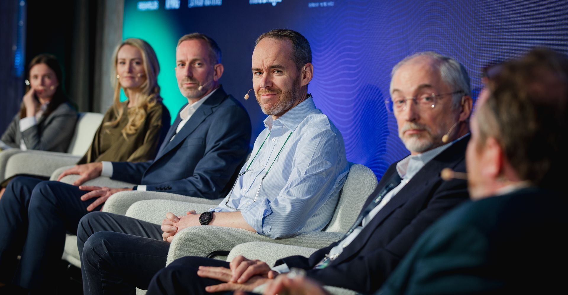 A photo taken by Ash Garwood of a man listening to a panel at a town-hall style corporate event.