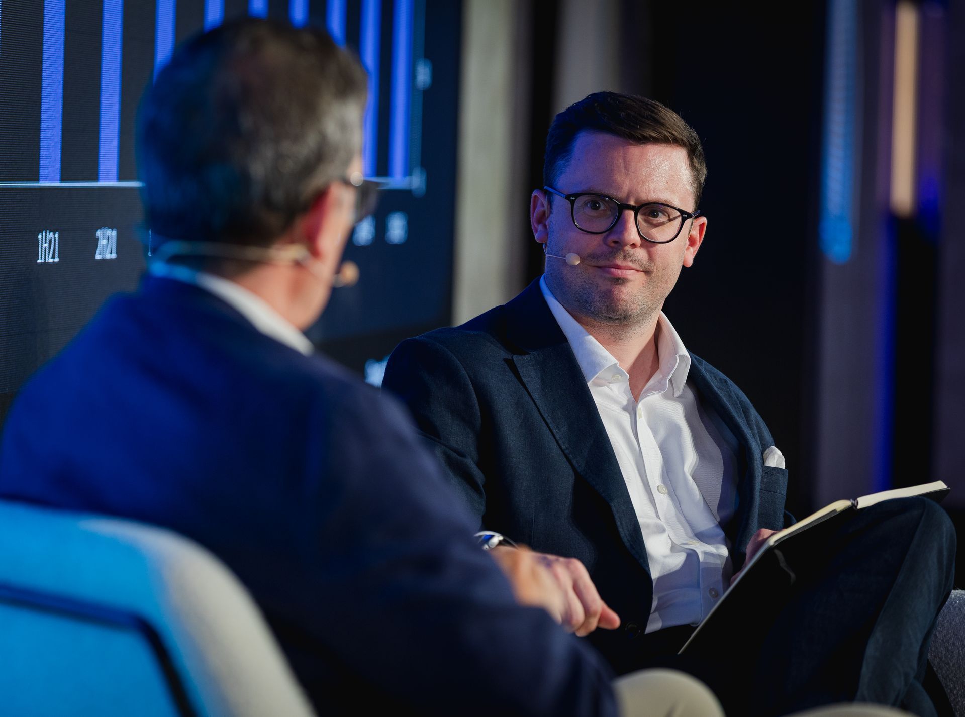 A photo taken by Ash Garwood of a man listening to a panel at a town-hall style corporate event.