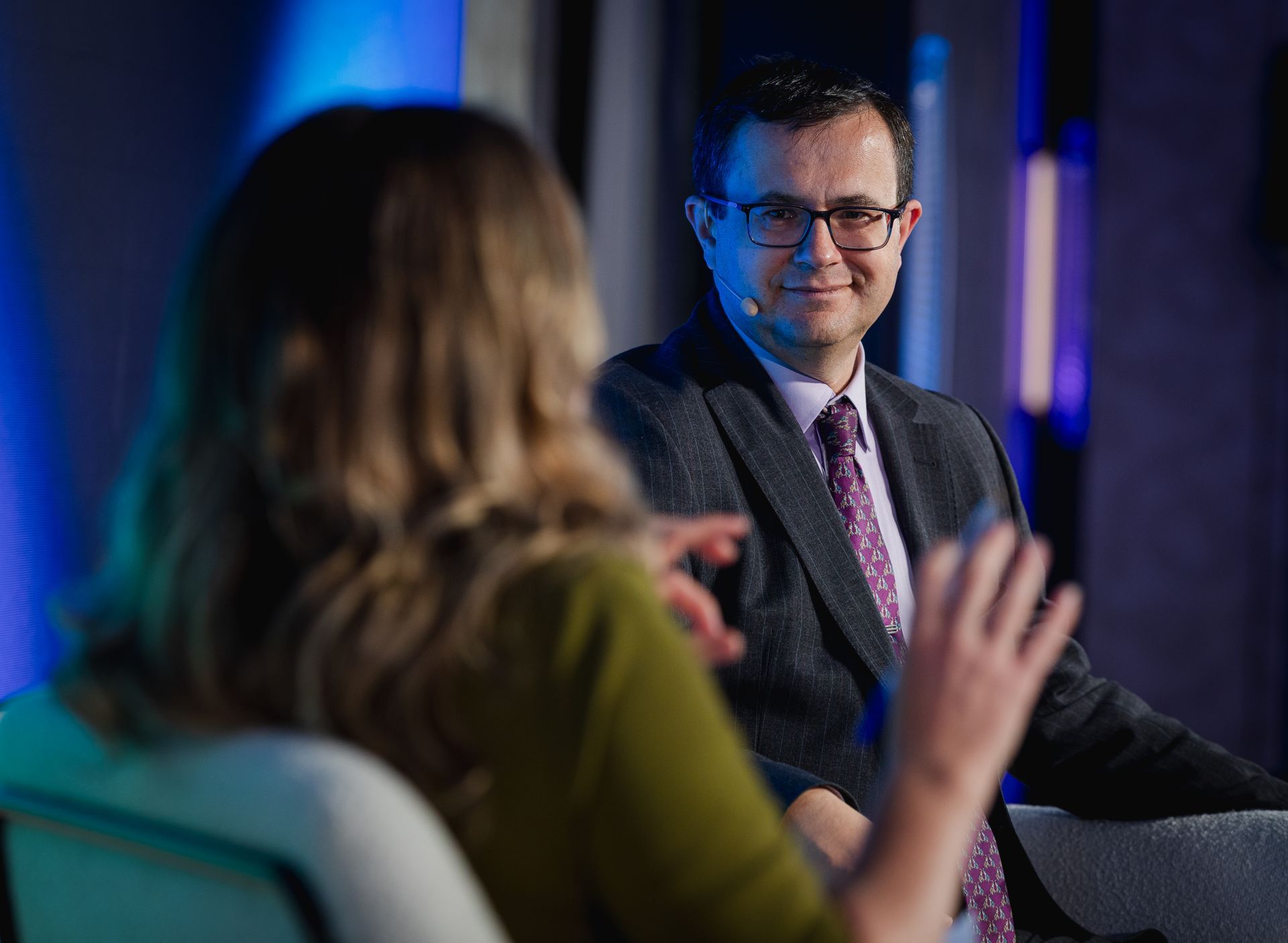 A photo taken by Ash Garwood of a man listening to a panel at a town-hall style corporate event.