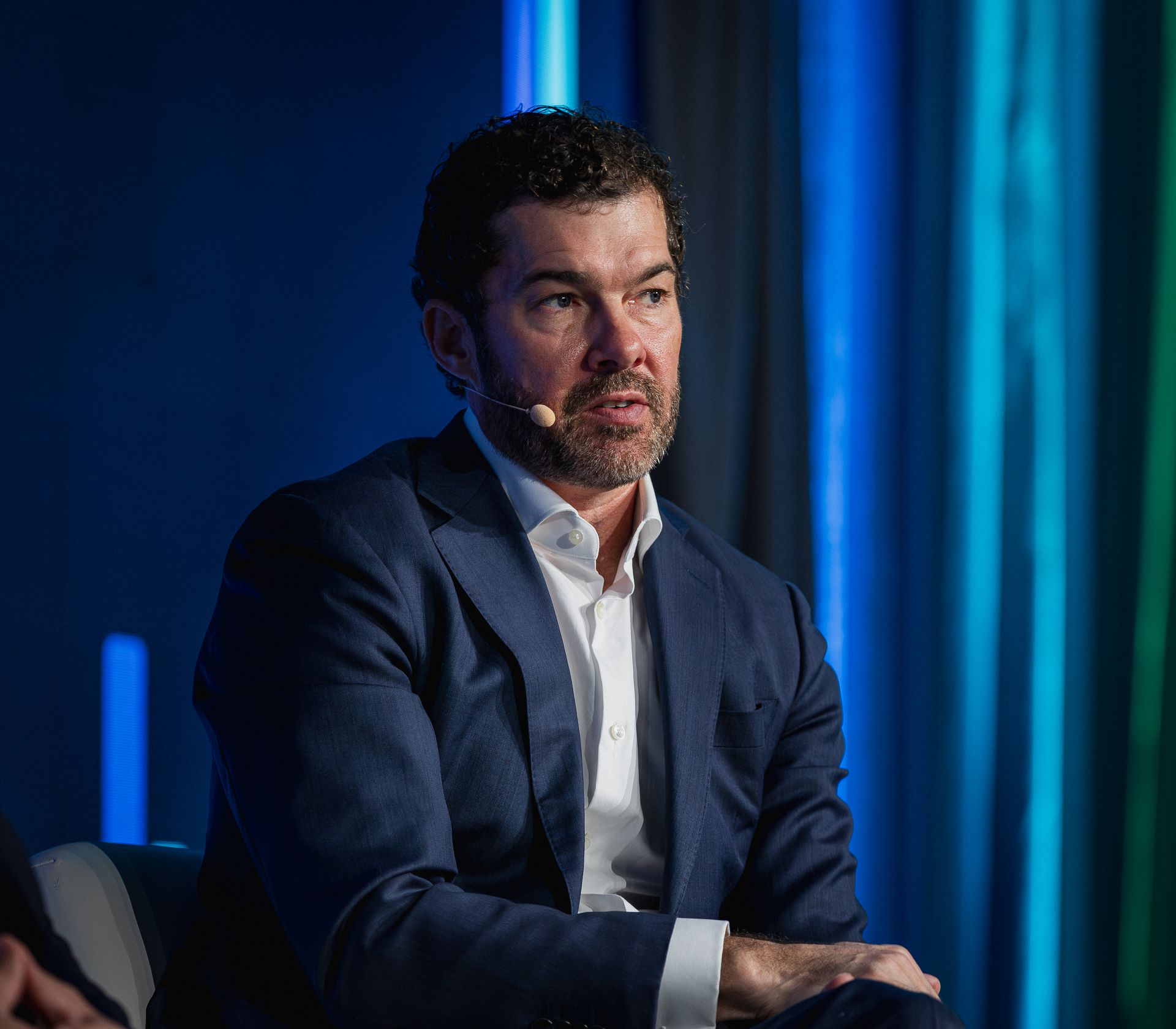 A photo taken by Ash Garwood of a man talking to a panel at a town-hall style corporate event.
