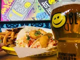 Tacos with fries and a glass of beer with a smiley face in a brewery.