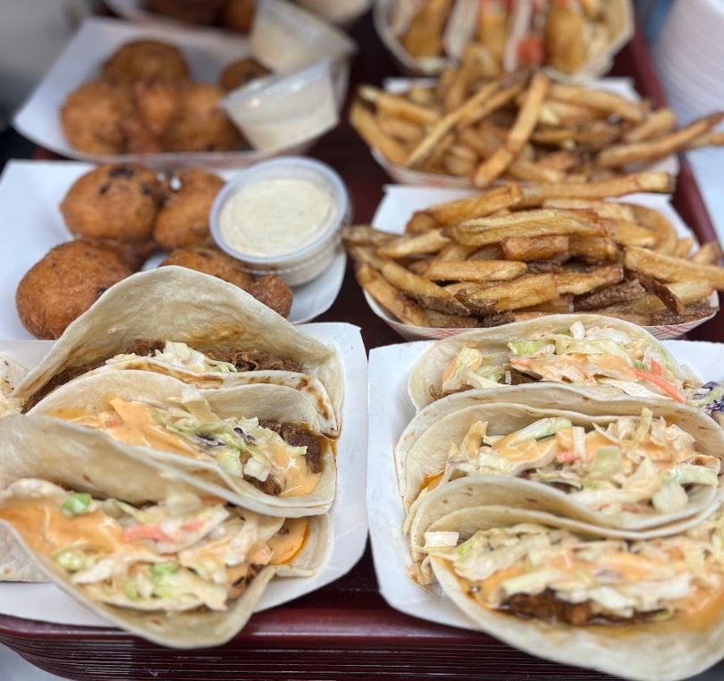 Platters of food: tacos, french fries, hushpuppies, and dipping sauces.