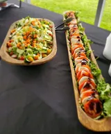 Two wooden serving trays with salads on a black tablecloth: Mixed salad and tomato mozzarella.