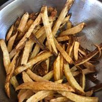 Bowl of golden-brown french fries, some with crispy edges.