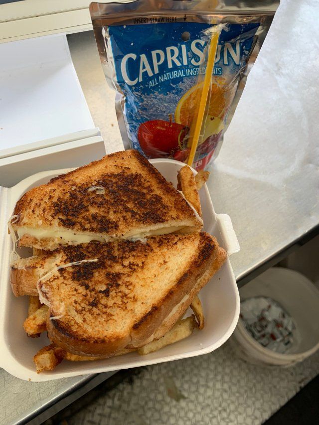 Grilled cheese sandwich and fries in a styrofoam container, with Capri Sun juice box.