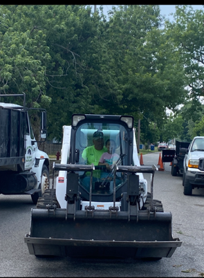 Fallen tree with exposed roots on ground, power line truck in background. Green trees and grass.
