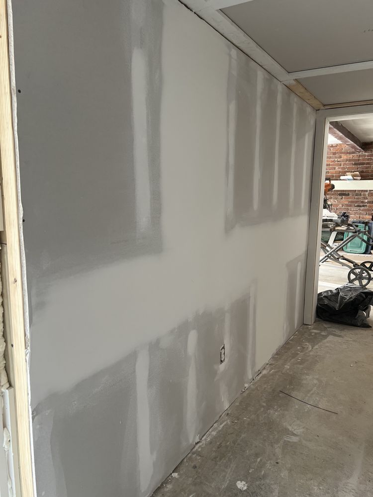 Drywall installation in a room, with visible seams and unfinished texture.
