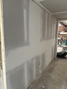Drywall installation in a room, with visible seams and unfinished texture.