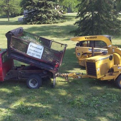 A red truck is being towed by a yellow machine.