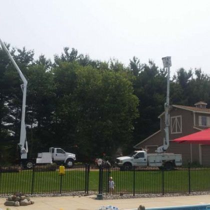 A white truck is parked in front of a fence next to a swimming pool.